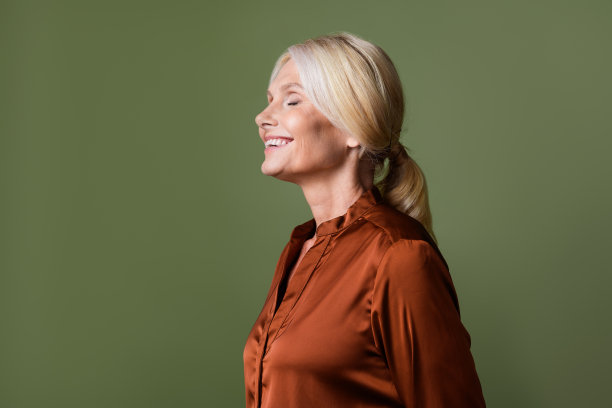 可爱的老夫人的照片肖像闻香气空空间穿着时髦的丝绸棕色服装孤立在卡其色背景图片下载