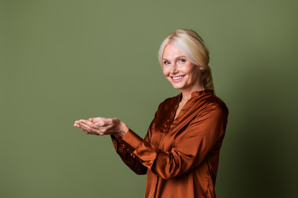 照片肖像迷人的退休妇女手掌握空空间穿着时尚的丝绸棕色衣服孤立的卡其色背景图片下载