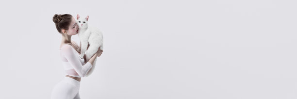 宠物收养服务的宣传图片，关注动物的优雅。温柔的小女孩坐在地板上，白猫映衬着白色的画室背景图片下载