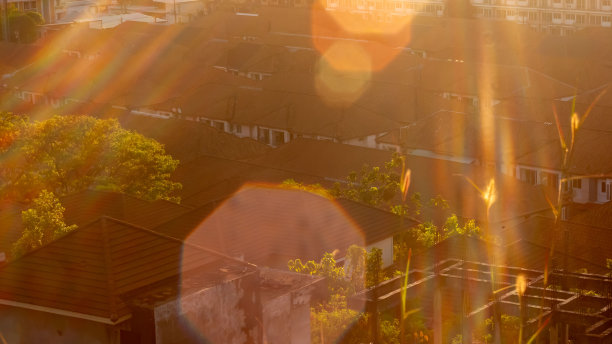 照片中，黎明笼罩着村庄的房屋，阳光刺眼。图片下载