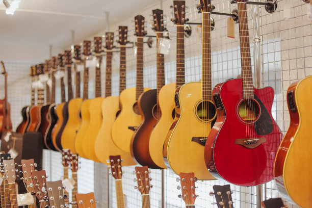 许多不同的原声吉他挂在音乐商店的墙上。关闭了。图片下载