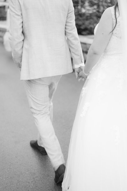 新郎和新娘手牵着手走在路上。后视图。裁剪。黑白照片图片下载