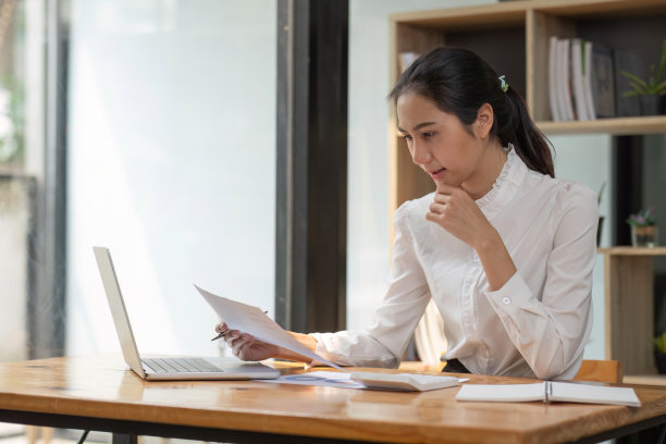 成功的亚洲女商人坐下来与数字和图表打交道。在办公室桌子上的笔记本电脑上图片下载
