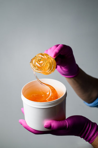 透明的浆糊装在塑料容器里，由一名穿着蓝色衬衫、戴着粉色手套的专家负责图片下载