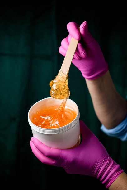 一个穿着蓝色衬衫，戴着粉色手套的女人用铲子拿着糖糊图片下载