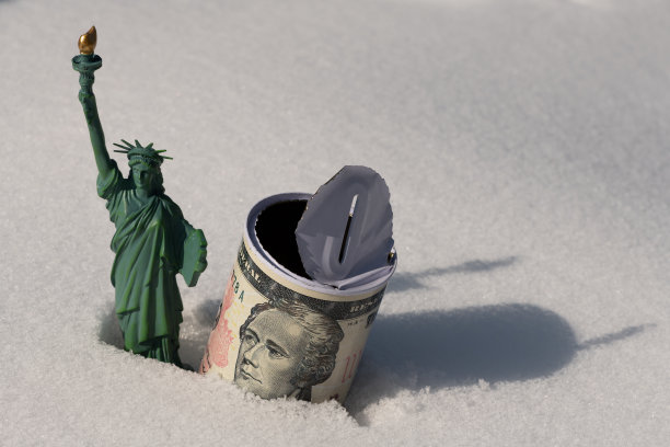 自由女神像和一个空的储蓄罐，上面有一张10美元钞票在雪地里的图片图片下载