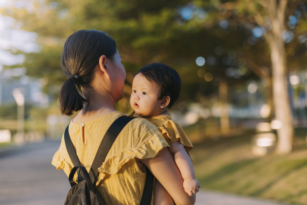 一位亚洲母亲在花园公园里抱着她的女婴。库存图片图片下载