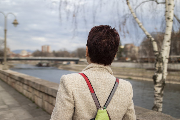 一位留着红色短发、戴着黄色太阳镜的多种族中年妇女，在镇上散步了很长时间。休闲优雅的风格。x世代。真实的人，下班后。春天开始的股票照片图片下载