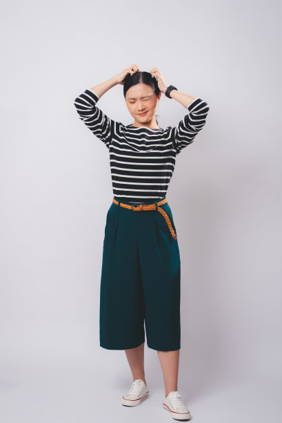 一个亚洲女人搔着头，孤立地站在白色的背景上。图片下载