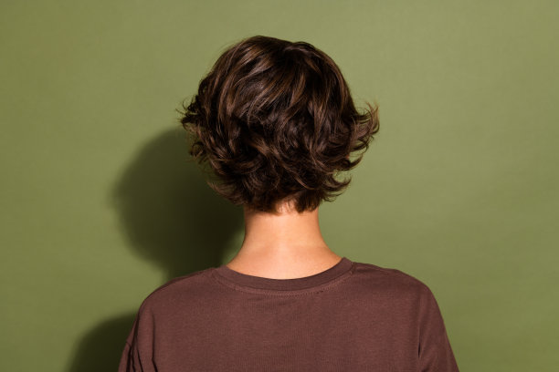 后面的后视图照片华丽的女孩与鲍勃发型穿着穿着t恤转身与她的背部孤立的卡其色背景图片下载