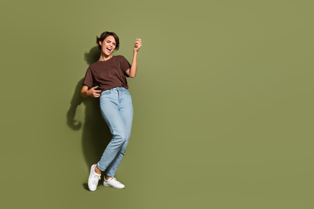 全尺寸照片积极的女人穿着棕色t恤玩想象吉他附近的空白空间提供孤立的卡其色背景图片下载