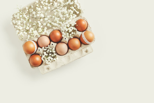 棕色复活节彩蛋装饰花边和白色的吉思非亚花在纸盒在白色的背景。复活节庆祝概念。节日食品的俯视图照片，涂上复古色调的鸡蛋图片下载
