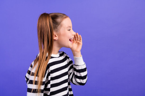 照片正面兴奋的小男孩穿着条纹套头衫告诉公告空白空间孤立的紫色背景图片下载