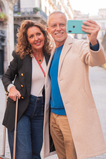 垂直的照片。深情的夫妻在度假时用智能手机自拍。两个人，一男一女，在旅游用手机拍照，笑着对着相机笑图片下载