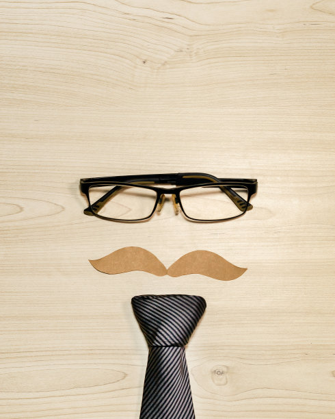 一个留着胡子、戴着眼镜的男人的脸被放在一个木制的表面上，上面写着“父亲节”图片下载