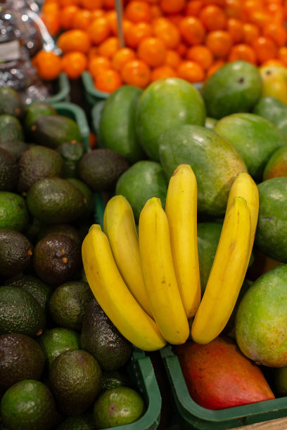 在商店里其他水果的背景下，一根香蕉树枝。图片下载