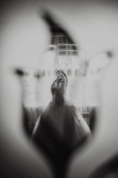 在新娘的房间里，一件精致的结婚礼服穿在一个有皇家装饰的人体模型上。镜子里的照片反射。黑白照片图片下载