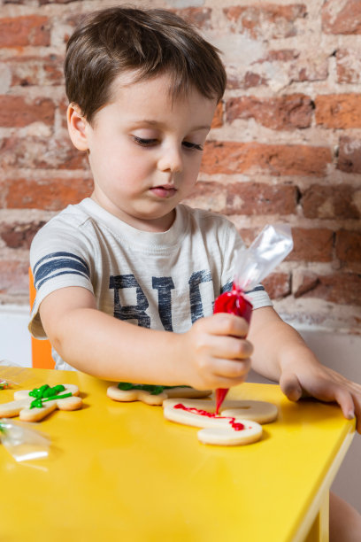 小男孩在家里黄桌子旁做饼干的照片图片下载