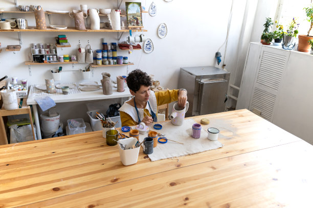 装饰陶瓷的过程:女陶艺家拿着画笔在陶罐上画装饰物图片下载