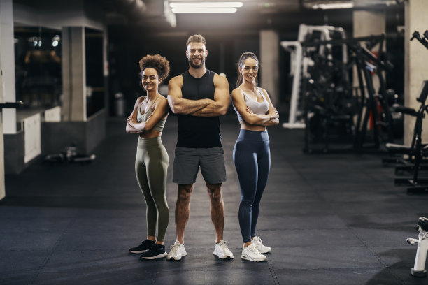 健美运动员在健身房里摆姿势，对着镜头微笑的照片。图片下载