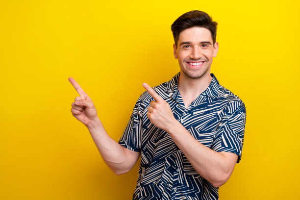 照片中心情良好的男人，留着时髦的发型，穿着蓝色的衣服，在黄色的背景上指向服务空间图片下载