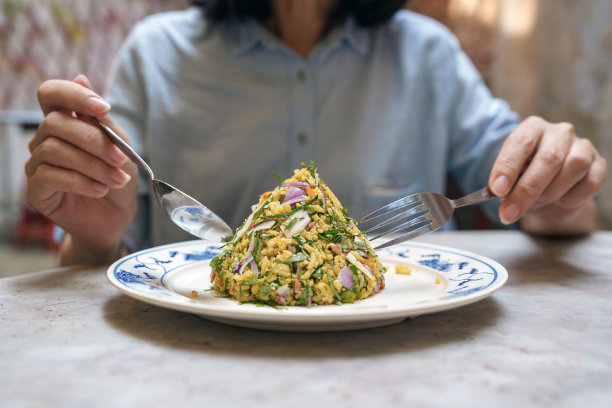 在这张裁剪过的图片中，一名妇女在街边的小摊上享用着传统的马来香草米Nasi Ulam。图片下载