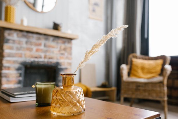 桌上有一瓶干花。斯堪的纳维亚的经典房间，木质细节和砖砌壁炉，简约的室内设计。一张真实的照片。舒适的房子。图片下载