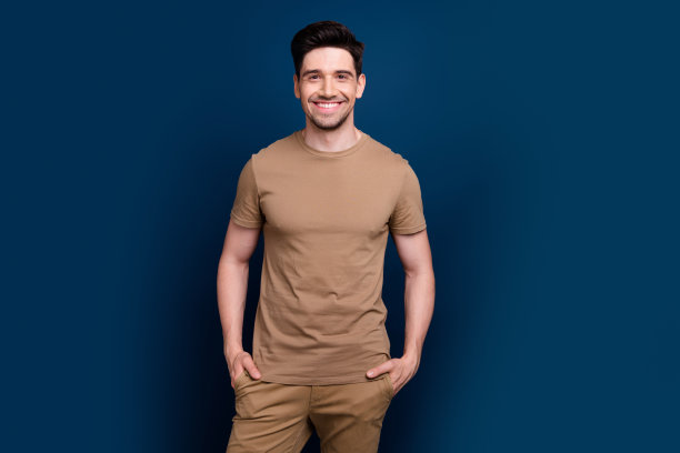照片积极的好男人穿米色柔和时尚的衣服，双手在口袋孤立的深蓝色背景图片下载