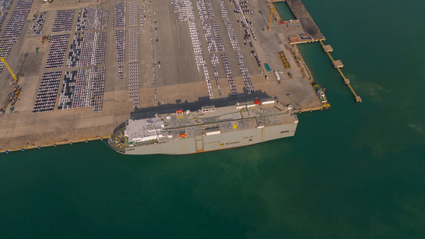 无人机拍摄的大型汽车运输船在拖船引导下停靠到地中海港口的照片图片下载