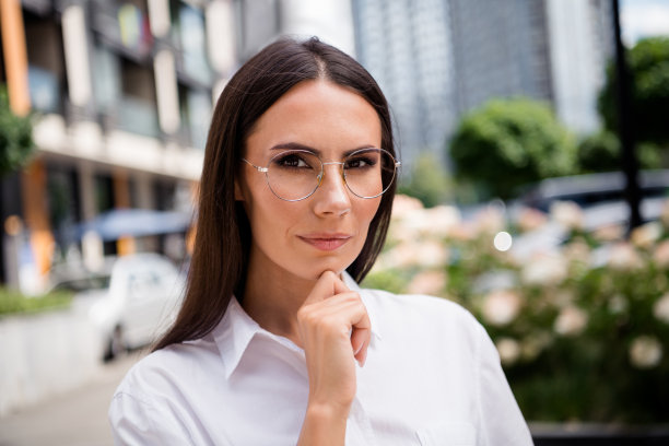 照片严肃聪明的女销售经理穿着白衬衫，戴着眼镜，手臂，手下巴户外城镇街道图片下载