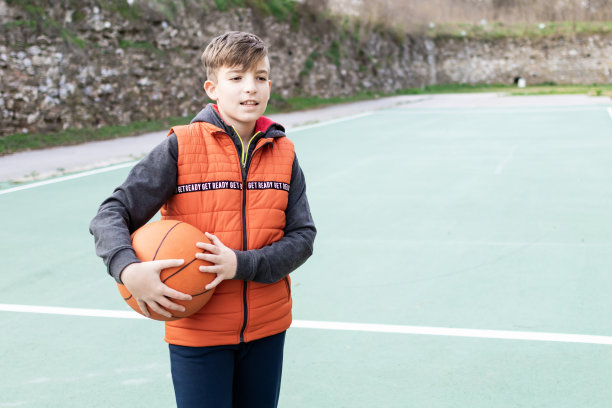 一个男孩在体育场上拿着篮球的照片。图片下载