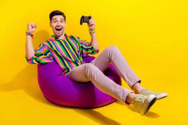 在办公室工作的年轻疯子的全身照片，有休息时间在休息室玩孤立的黄色背景的游戏机图片下载