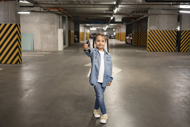 小女孩穿着便服站在地下停车场拿着钥匙图片下载