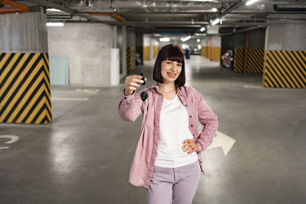 一个穿着便服站在地下停车场拿着钥匙的女人。图片下载