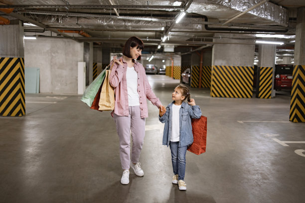 妈妈和小女儿，穿着便服，走在地下停车场。图片下载