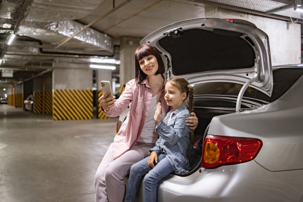 母女俩在地下停车场用智能手机自拍。图片下载