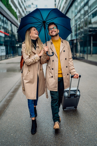 一对美丽的微笑着的年轻夫妇在雨中散步图片下载