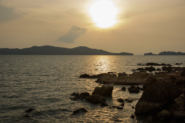 海滨日落的风景。日落海岩地平线视图。海岩日落剪影。日落海岩和山脉。自然背景图片下载