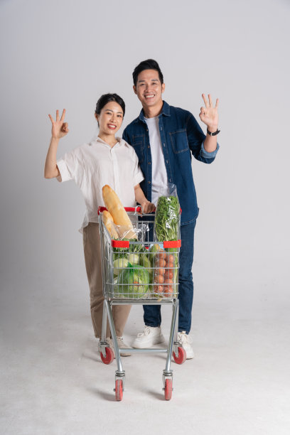 亚洲夫妇推着超市购物车购物的图片，孤立在白色背景上图片下载