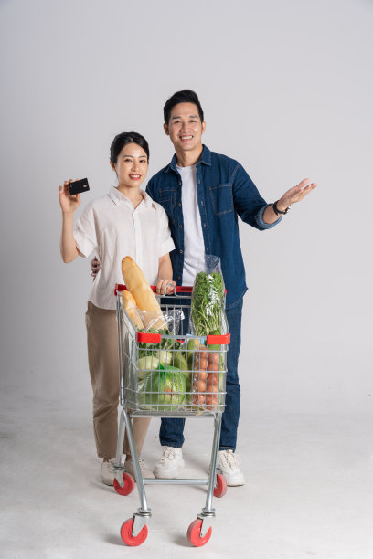 亚洲夫妇推着超市购物车购物的图片，孤立在白色背景上图片下载