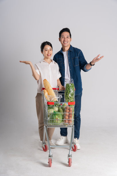 亚洲夫妇推着超市购物车购物的图片，孤立在白色背景上图片下载