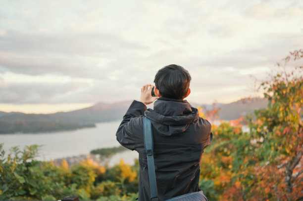 秋天，一些亚洲男性在日本旅行，他们使用数字设备连接技术，在日本天之浜山顶的旅游景点向她的朋友上传照片图片下载