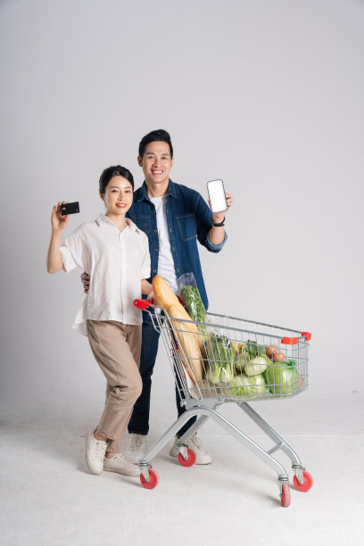 亚洲夫妇推着超市购物车购物的图片，孤立在白色背景上图片下载