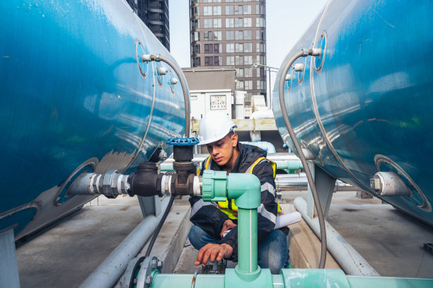 这张照片拍摄的是一位技术熟练的工程师在检查石化设备中的管道网络。具有与石化、工程和工业检验相关的项目概念。图片下载