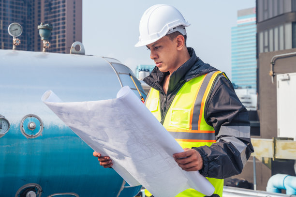 这张照片拍摄的是一位技术熟练的工程师在检查石化设备中的管道网络。具有与石化、工程和工业检验相关的项目概念。图片下载