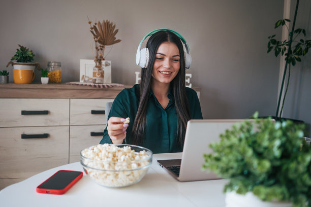 一个年轻女子一边看电影一边吃爆米花。图片下载