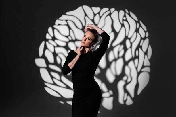 工作室的艺术照片的美丽性感的年轻女子，一个女商人，谁坐在聚光灯的中心光束。图片下载