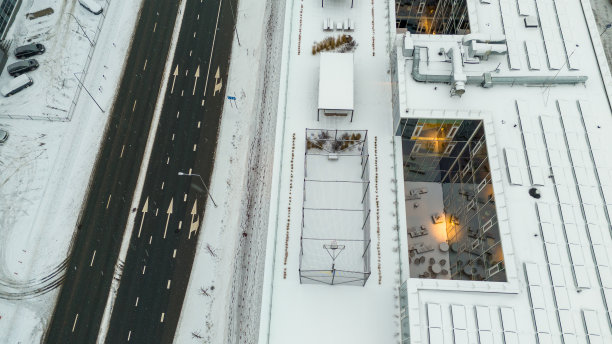 无人机拍摄的小篮球场，长凳和一个在冬天被雪覆盖的屋顶上放松的地方图片下载