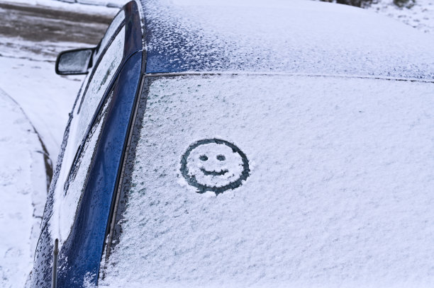 一个笑脸的象征被画在车上的雪上。冬天的概念。图片下载