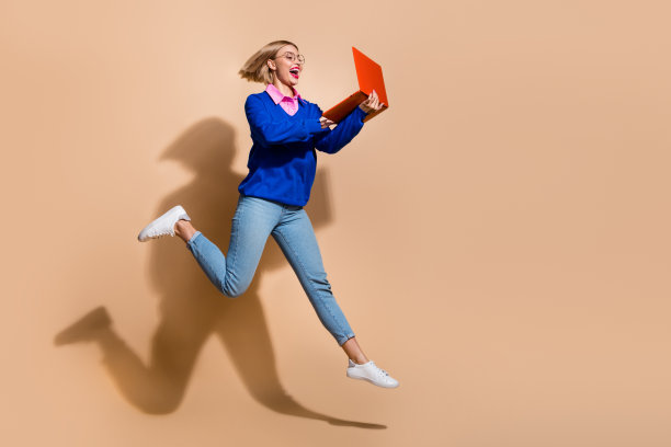 项目经理的全身尺寸的照片，年轻女子在it行业工作远程与红色笔记本电脑孤立的米色背景图片下载